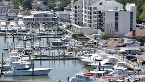 A marina with multiple boats docked, surrounded by residential buildings and a large white building with multiple windows. - Panoramic Ocean Views | Modern Kitchen|Heated Pool 1304 (Virginia Beach)