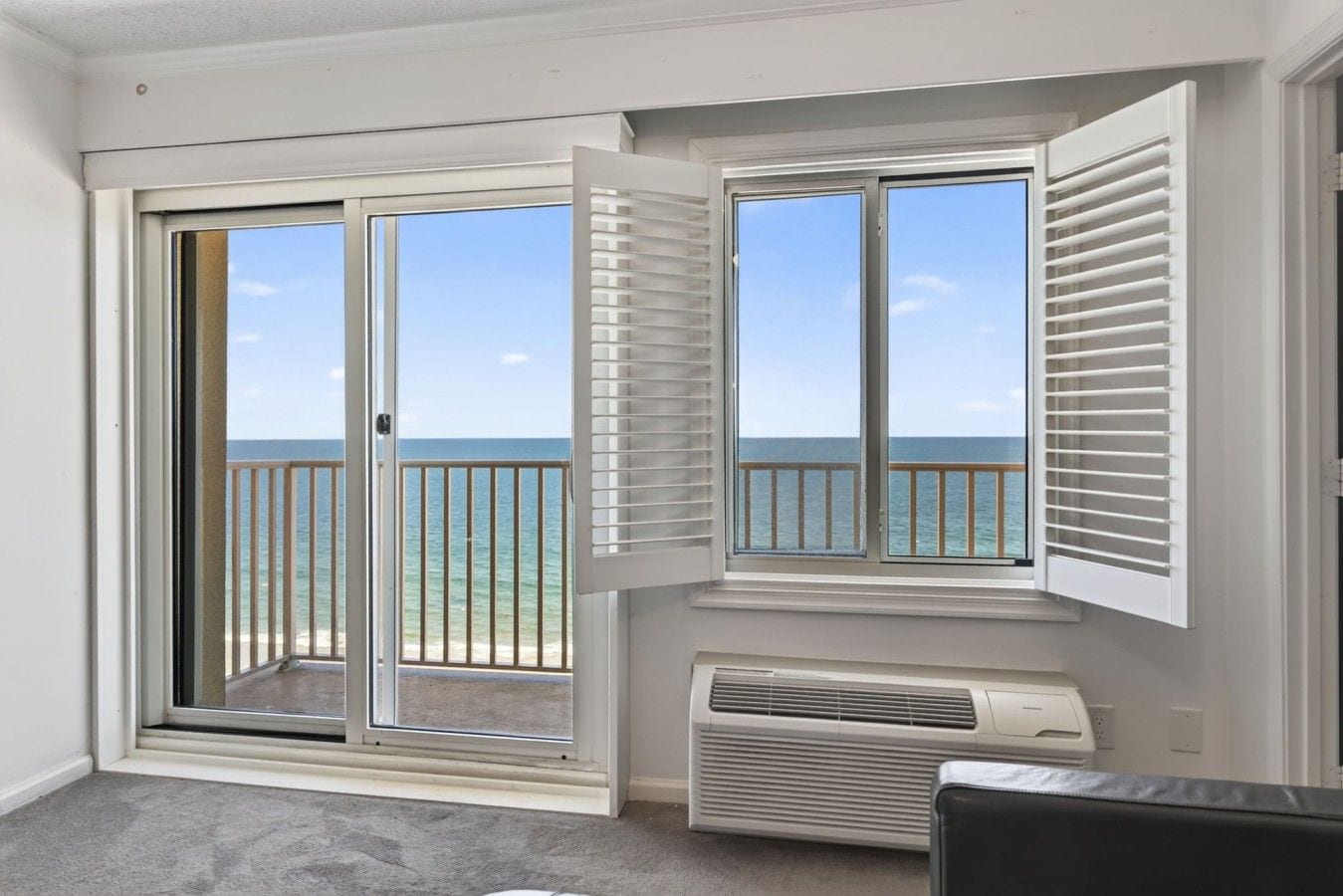 A room with a view of the ocean through a sliding glass door.