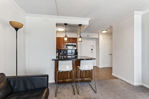 A modern kitchen with a bar area, wooden cabinets, and pendant lighting.