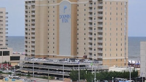 A high-rise hotel with a prominent 'Dolphin Run' sign, multiple balconies, and a parking structure below. - Panoramic Ocean Views | Modern Kitchen|Heated Pool 1304 (Virginia Beach)