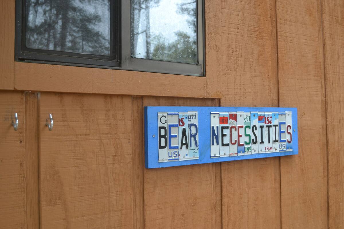 Eine Holzwand mit zwei Nummernschildern, eines zeigt 'BEAR' und das andere 'NECESSITIES'.
