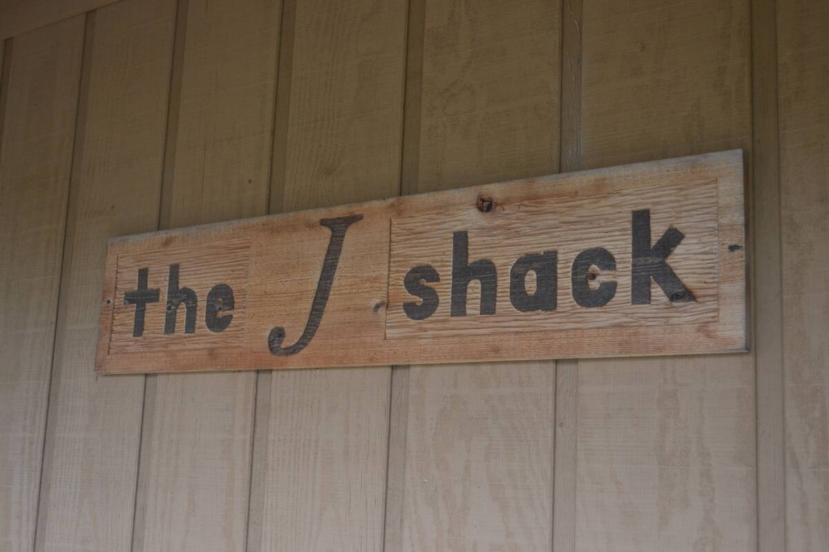 Ein hölzernes Schild mit dem Aufschrift "the J shack" an einer Holzwand befestigt.