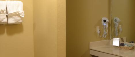 A bathroom with a toilet, a towel rack, a hairdryer, and a mirror.
