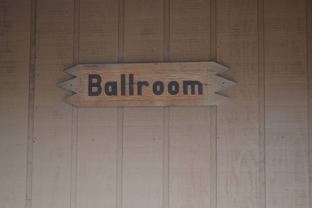 Ein Holzschild mit dem Wort "Ballroom" an einer Holzwand.