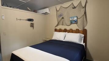 A single bed with a white and blue bedspread, a wooden headboard, and a ceiling light fixture.
