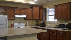 Una cocina con armarios de madera, un refrigerador blanco, una estufa y un microondas.