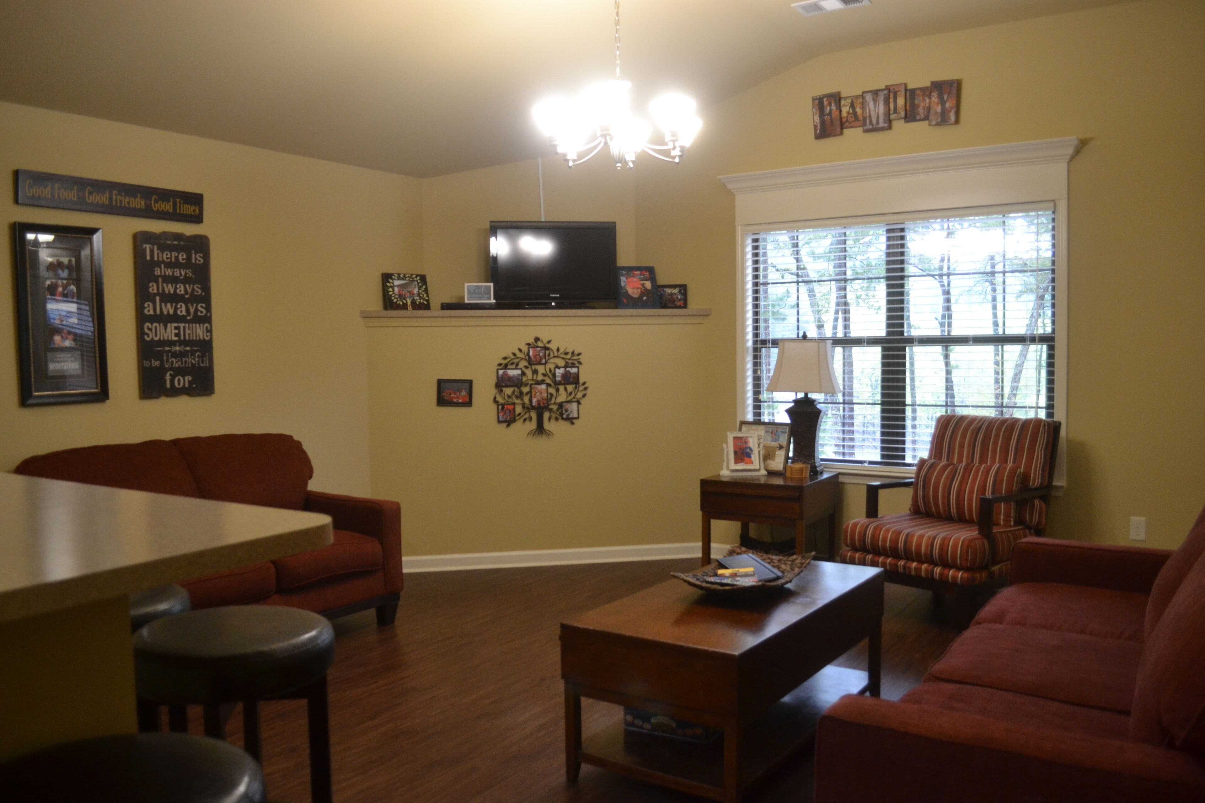 A living room with a sofa, armchair, coffee table, and a TV on a stand.