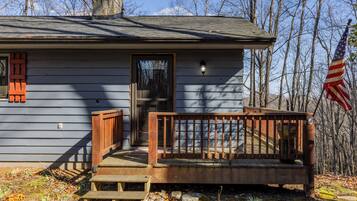 A wooden cabin with a porch, a chimney, and an American flag.