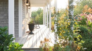 A wooden deck with a white railing, potted plants, and outdoor furniture. - Luxury Rental Located In New Glasgow, Minutes To Amazing Restaurants and Beaches (New Glasgow)