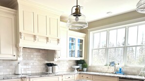 A kitchen with white cabinetry, a marble countertop, and a large window. - Luxury Rental Located In New Glasgow, Minutes To Amazing Restaurants and Beaches (New Glasgow)