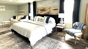 A bedroom with a large bed, a chair, a small table, and a painting on the wall. - Luxury Rental Located In New Glasgow, Minutes To Amazing Restaurants and Beaches (New Glasgow)