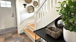 A staircase with a black metal table, wicker baskets, and a potted plant. - Luxury Rental Located In New Glasgow, Minutes To Amazing Restaurants and Beaches (New Glasgow)