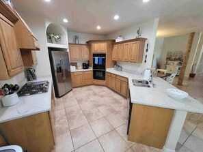 A modern kitchen with wooden cabinets, a stainless steel refrigerator, and a marble countertop.