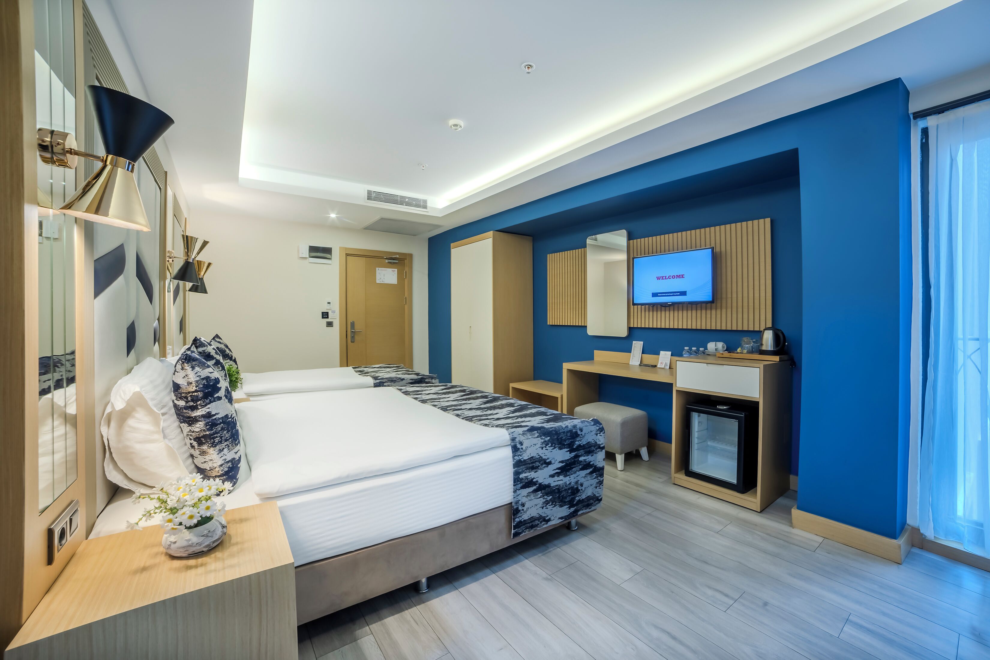 Une chambre d’hôtel équipée d’un lit, d’une table de chevet, d’une télévision, d’un bureau, d’une chaise et d’un petit réfrigérateur.