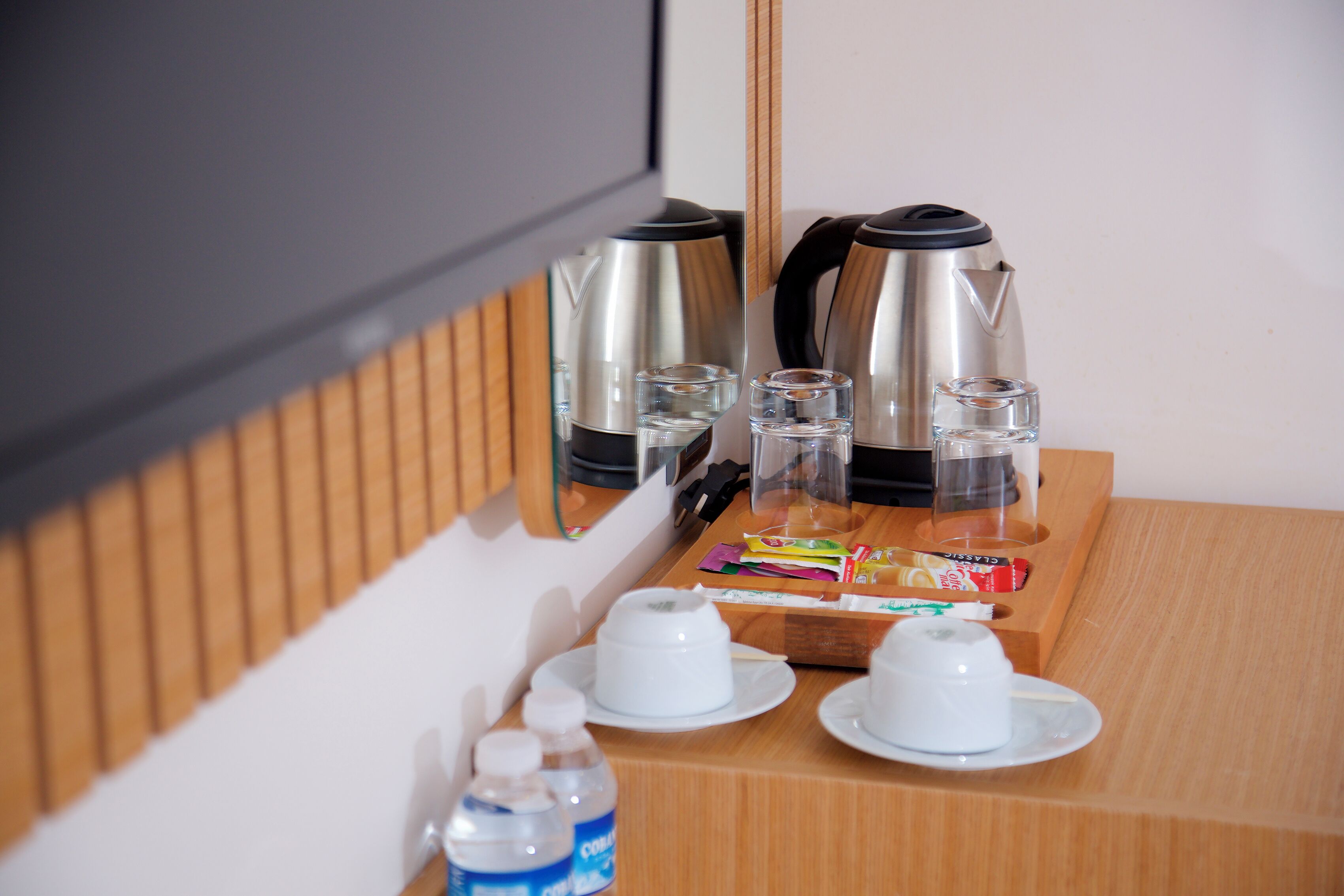 A breakfast setup with a coffee maker, cups, and a tray with condiments.