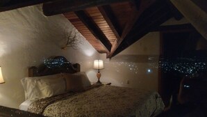 Un dormitorio con cama, lámpara y vistas de las luces de la ciudad por la noche.