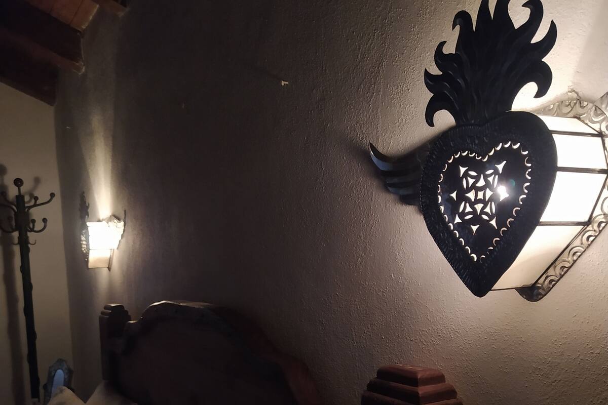 A dimly lit room with a bed, a wall-mounted decorative heart-shaped light fixture, and a wall-mounted light.