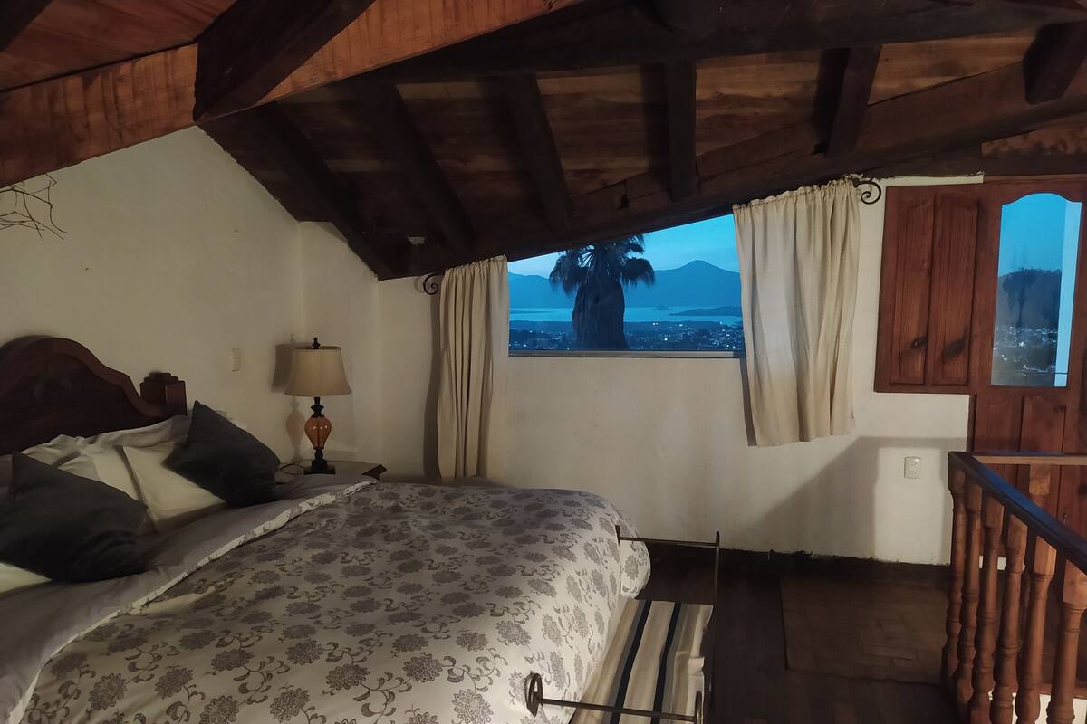 A bedroom with a bed, a nightstand, a lamp, and a window with curtains.