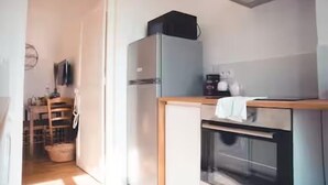 Una cocina compacta con refrigerador, horno y una pequeña encimera.
