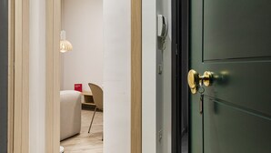 L'ingresso di una camera d'albergo con una porta verde scuro, un moderno lampadario e un tavolino con una sedia.