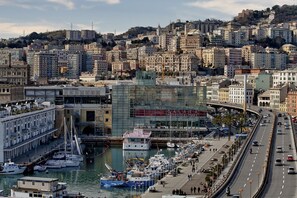 A marina with boats docked, a road parallel to the water, and buildings in the background. - Goletta Studio by Wonderful Italy (Genova)