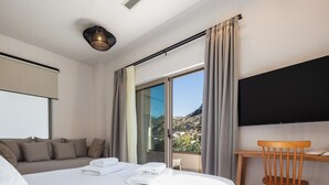 Habitación de hotel moderna con cama, escritorio, silla y un amplio ventanal con vistas a la montaña.