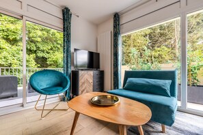 A modern living room with a sofa, a chair, a TV, and a dining table. - Domaine des Rives D'ormoy : Moorea (Ormoy-la-Rivière)