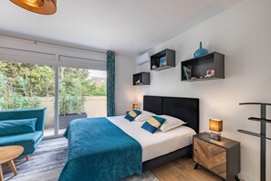 Quarto de hotel moderno com cama, mesa de cabeceira, escrivaninha e sofá.