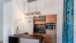 A modern kitchen with a wooden island, built-in appliances, and pendant lighting. - Domaine des Rives D'ormoy : Moorea (Ormoy-la-Rivière)