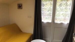Une pièce avec un lit jaune, une petite table ronde et une fenêtre avec des rideaux.