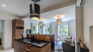 A modern kitchen with a central island, wooden cabinetry, and pendant lighting. - Domaine des Rives D'ormoy : Athamante (Ormoy-la-Rivière)