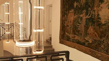 A staircase with a black metal railing and a large tapestry on the wall.