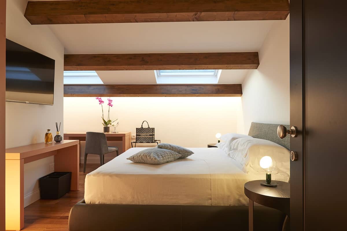 A bedroom with a bed, desk, chair, and skylight.