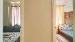 Un corridoio stretto che porta a due camere da letto, ciascuna con un letto e una finestra.