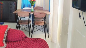Una stanza con un letto, un tavolo con sedie, una televisione e una finestra con tende.
