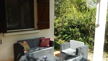 A patio with wicker furniture, a cushioned sofa, and a small table.