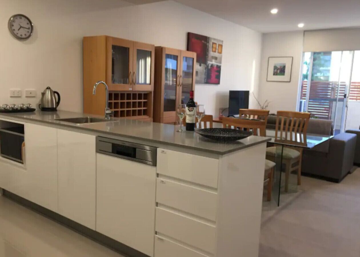 Una cocina moderna con una isla central, armarios de madera y una zona de comedor con mesa y sillas.