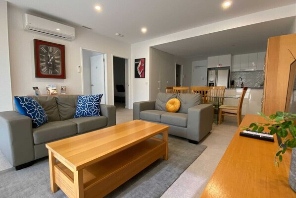 A modern living room with two sofas, a wooden coffee table, and a dining area with a table and chairs.