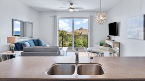 A modern kitchen with a double sink, a ceiling fan, and a dining area with a table and chairs. - Gulf Views - Beach Chair Service - Zero Entry Pool + Hot Tub - Beach Resort 403 (Miramar Beach)