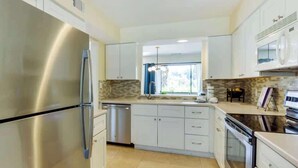 A modern kitchen with stainless steel appliances, white cabinetry, and a tiled backsplash. - Luxury Villa Golf Beach & Pool Access Hilton Head (Hilton Head Island)