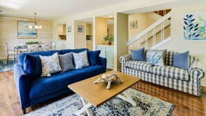 A living room with a blue sofa, a checkered sofa, a wooden coffee table, and a staircase. - Luxury Villa Golf Beach & Pool Access Hilton Head (Hilton Head Island)