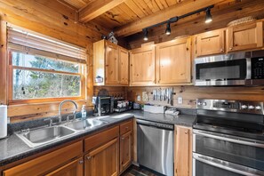 A kitchen with wooden cabinets, stainless steel appliances, a dishwasher, and a window with blinds. - Majestic views on 3 luxurious levels. Workspace and Game Room. (Gatlinburg)
