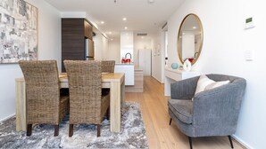 Una sala de estar moderna con comedor, un sillón gris y un espejo grande.