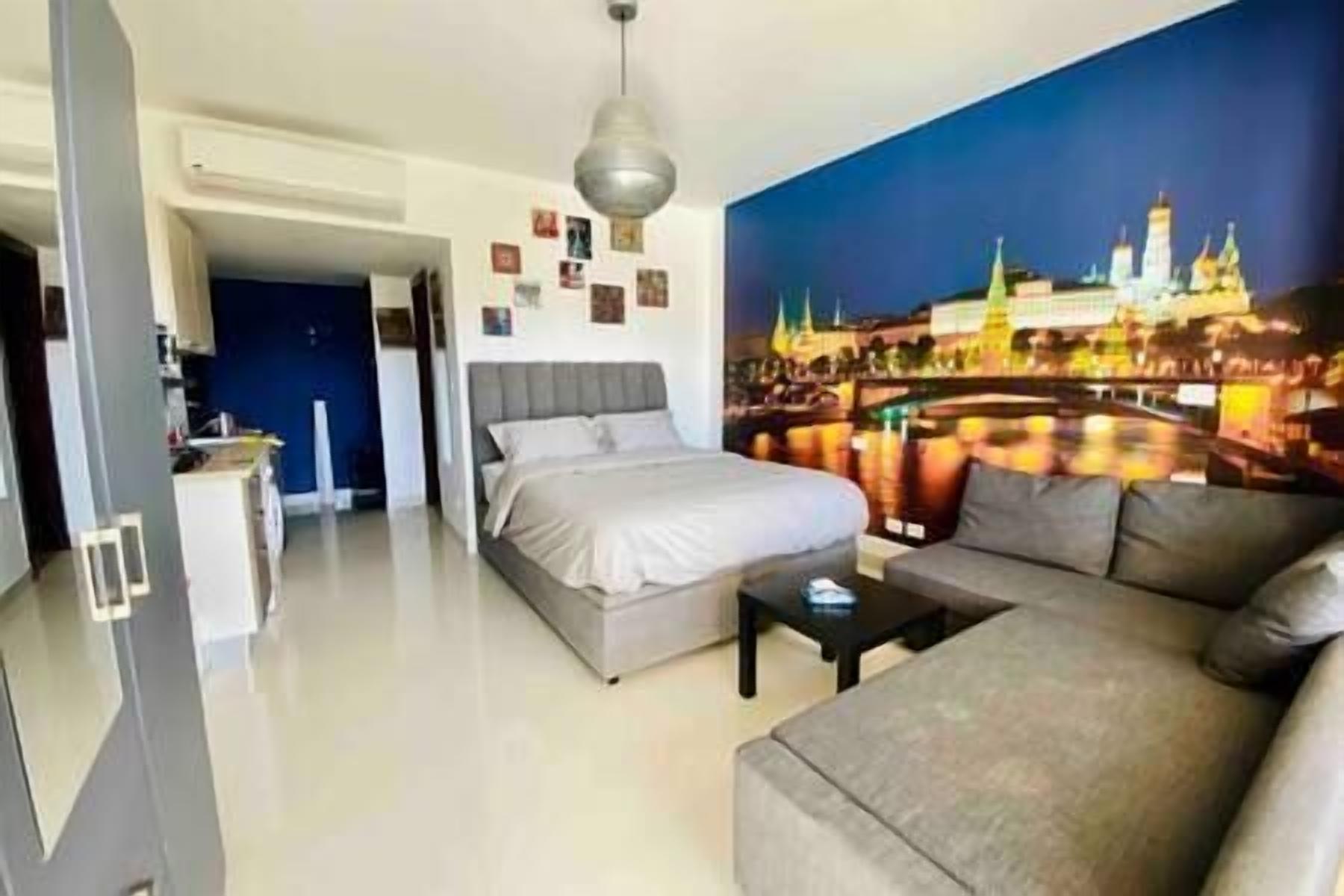 A bedroom with a bed, a sofa, and a cityscape mural on the wall.