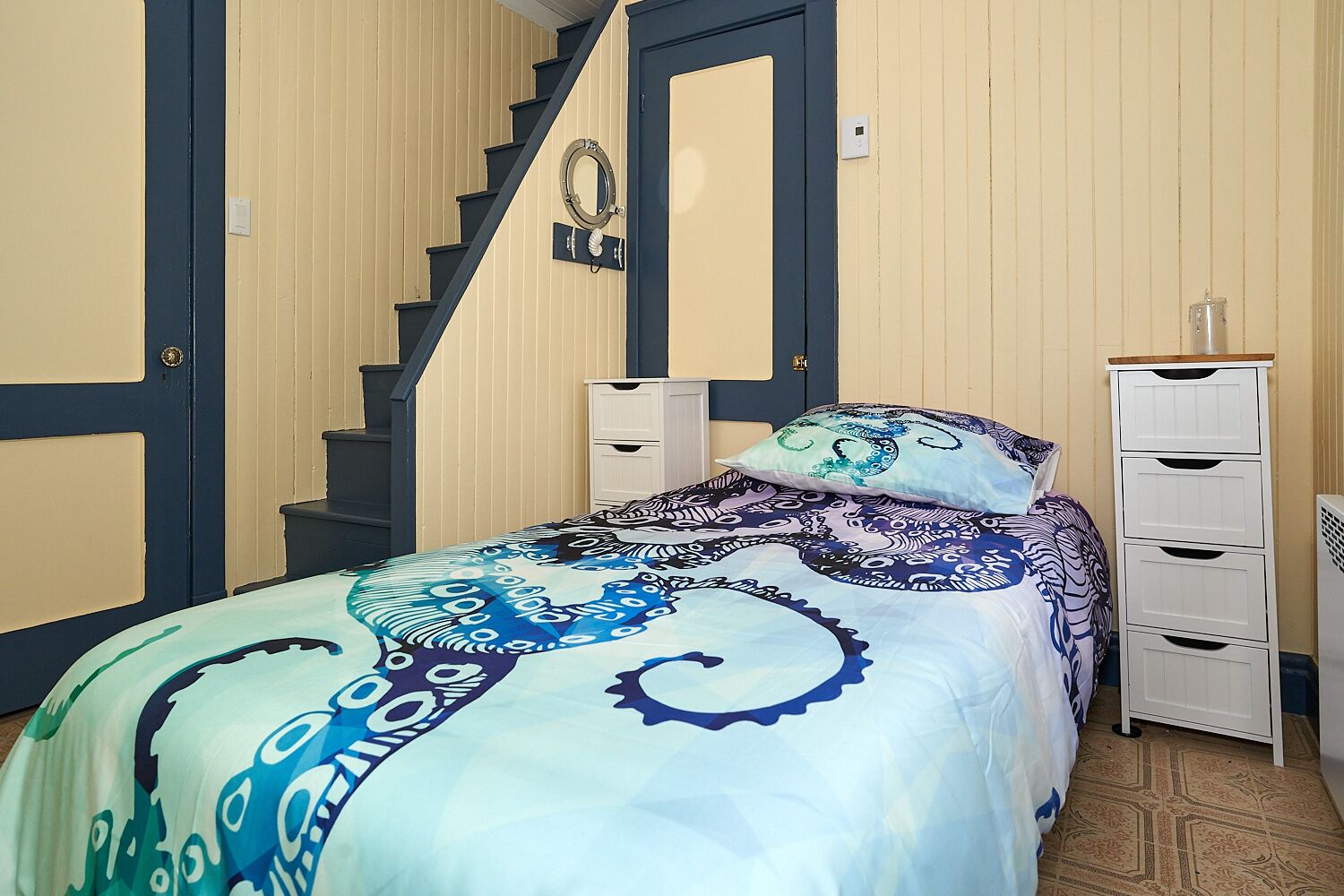 Une chambre à coucher avec un lit, une commode, un miroir et un escalier.