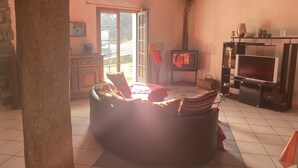 A cozy living room with a fireplace, a sofa, and a television. - Gite Lasterenborda (Osses)