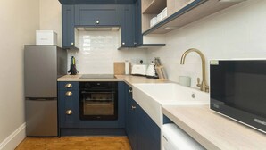 Una cocina compacta con horno empotrado, refrigerador, pileta y microondas.
