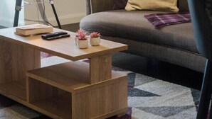 A cozy living room with a sofa, a coffee table, and a floor lamp. - Perth Penthouse at the Concert Hall (Perth and Kinross)