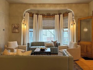 A cozy living room with a sofa set, a coffee table, and a window with curtains.