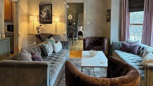 A living room with a sofa, armchair, and coffee table. There is a dining area with a table and chairs. A chandelier hangs from the ceiling. - Epic 8BR Milwaukee Victorian House (Milwaukee)